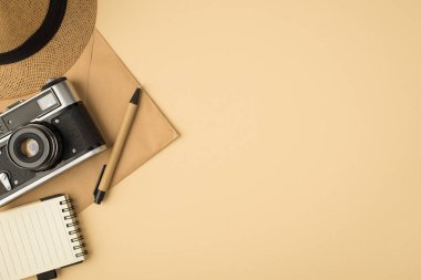 Kapak kalem telif defteri ve kameranın üst görünümü kapalı bej arkaplan üzerindeki el işi kağıt zarf ve telif alanı ile kamera