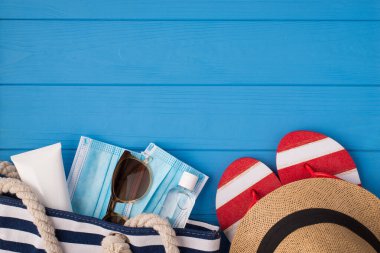 Güneş kremi antiseptik güneş gözlüğü takan çantanın mavi arka planda izole edilmiş, boş alan olan sandaletleri.