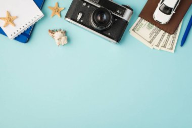 Not defterlerinin en üstteki fotoğrafı pasaport kapağındaki kalem araba modeli dolar ile deniz kabuğu ve izole edilmiş pastel mavi arka planda deniz balıkları.