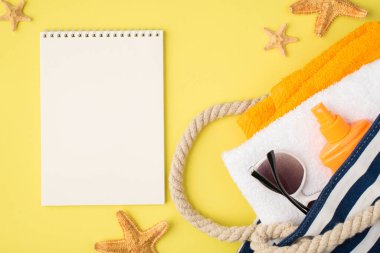 Yıldız balıklarının plaj çantalarında havlular turuncu şişe güneş kremi ve izole edilmiş sarı arka planda boş alan ile güneş gözlüğü.