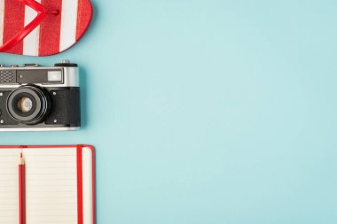 Çizgili parmak arası terliklerin üst görünümü kırmızı kalem ve açık günlük izole edilmiş pastel mavi arkaplan ve sağ telif alanı