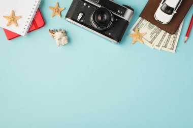 Pasaport kapağındaki kırmızı fotokopi kitaplarının, kalem araba modelinin deniz kabuğu ve deniz balıklarının izole edilmiş pastel mavi arka planda fotokopi çekimleri.