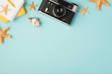 Sarı defterlerin en üstteki fotoğrafı kalem kameralı deniz kabuğu deniz kabuğu balıkları ve izole edilmiş pastel mavi arkaplanlı kamera.