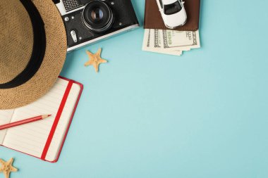 Kırmızı kalem planlayıcısı ve pasaport kapağındaki araba modeli ve kırmızı kalem planlayıcısının en üst görüntüsü. Kopyalama alanı ile izole edilmiş pastel mavi arka planda dolarlarla.