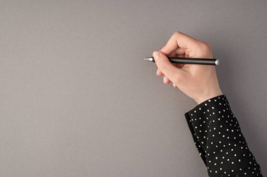 İzole edilmiş gri arka planda, kadın eli kalem tutarken çekilen ilk fotoğrafın kopyası