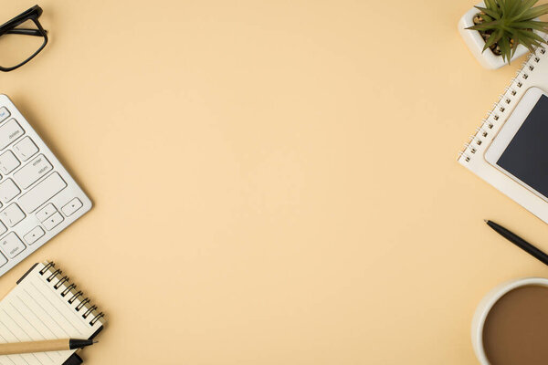 Вид сверху фото чашки очки цветочный горшок ручки смартфон два ноутбука и клавиатура на изолированном бежевом фоне с копирайтом в середине