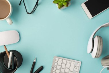 Fare kalemlerinin, kalem tutacaklarının, klavye kulaklıklarının üst görüntüsü akıllı telefon bitkilerinin ve gözlüklerin izole edilmiş pastel mavi arkaplanlarının ortasındaki kopyalanmış boşlukların.