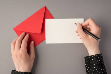 Beyaz kâğıt üzerinde kalem tutan ilk kişinin resmi. Kapalı kırmızı zarf, izole edilmiş gri arkaplan ve boş alan.