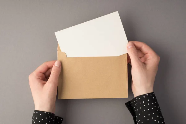 白地に白地のカードが入ったオープンクラフト紙の封筒を持つ女性の手の最初の人のトップビュー写真空白のスペース — ストック写真