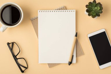 Organizatörlerin orta fincan kahve kadehindeki kalemlerinin ve izole edilmiş bej arka plandaki boş alandaki akıllı telefon ekranının en üst görünümü