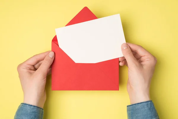 白地に白い紙のカードが描かれた開いた赤い封筒を持った女性の手の一番上の写真 — ストック写真