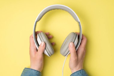 Sarı arka planda, kadın ellerinin kulaklık tutarken çekilmiş ilk resmi.