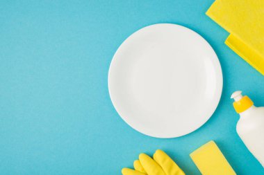 Mavi arka planda izole edilmiş sabun temizleme bezi sarı eldiven ve plaka fotoğrafı