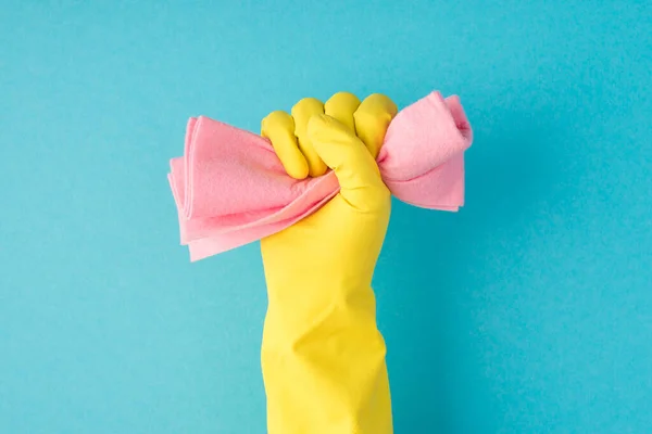 黄色の手袋で手を上げるの写真コピースペースと隔離された青の背景にピンクのラグを食いしばる — ストック写真