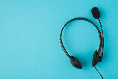 Üzerinde mikrofon olan siyah kulaklıkların, izole edilmiş mavi arkaplanlı ve kopyalanmış fotosu.