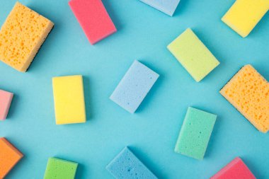 İzole edilmiş mavi arkaplanda çoklu renk temizleme pedlerinin üst görünümü