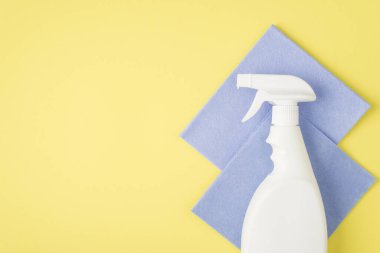 Etiketsiz sprey deterjan beyaz şişe ve izole edilmiş sarı arka planda iki gri yapışkan bez.