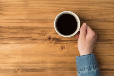 Ellerindeki kahve fincanının üstünde. Ahşap arka planda izole edilmiş.