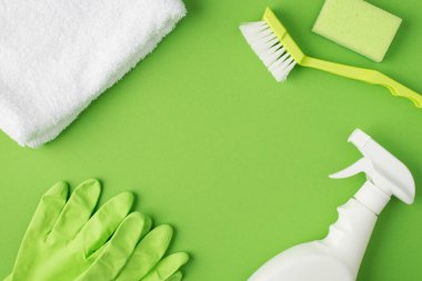 Beyaz havlu fırçası, sünger, deterjan şişesi ve yeşil lastik eldivenlerin izole edilmiş yeşil arka plan ve boş alan.