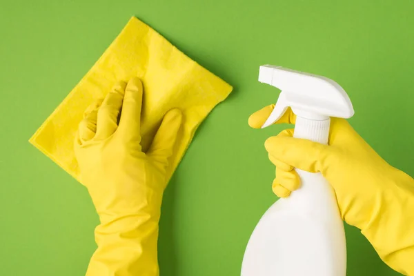 以上照片为双手戴黄色手套 手握清洁剂及在绿色背景上隔离的抹布的照片 — 图库照片