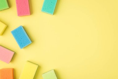 İzole edilmiş sarı arkaplandaki çok renkli süngerlerin sağ telif alanının üst görünümü