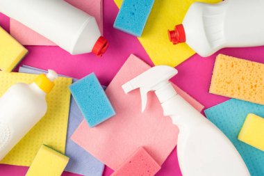 Deterjan sprey şişelerinin en üstteki fotoğrafı. Çoklu renkli peçeteler. İzole edilmiş pembe arka planda.