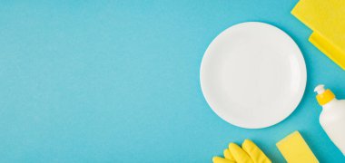 Mavi arka planda izole edilmiş sabun temizleme bezi sarı eldiven ve plaka fotoğrafı