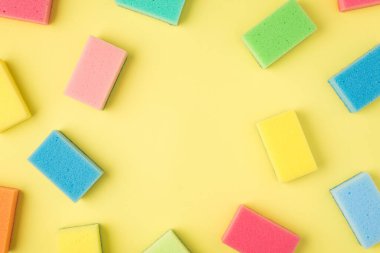 İzole edilmiş sarı arkaplandaki çoklu renkli süngerlerin ortadaki telif boşluğuyla en üstteki görünüm fotoğrafı