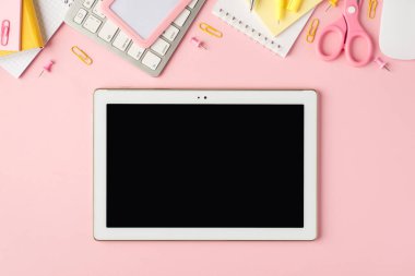 Pembe ve sarı kırtasiye resimlerinin üst görüntüsü kalemleri, raptiyeleri, makasları, çıkartmaları, fareleri ve tablet bilgisayarları boş alan arkaplanlı izole edilmiş pastel pembe arkaplanı hatırlatır.