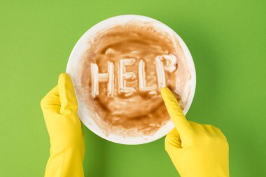 Sarı lastik eldivenli ellerin temiz olmayan tabağı tutarken ve yeşil arka planda işaret parmağına yardım ederken en üstteki fotoğrafta.