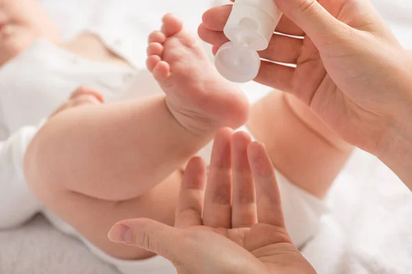 Крупный План Ноги Новорожденного Руки Матери Белой Кремовой Трубкой Изолированном — стоковое фото