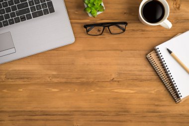 Dizüstü bilgisayarın en iyi görüntüsü gözlüklü kahve fincanı ve kalem iki planlayıcının üzerinde kopyalanmış ahşap masa zemininde.