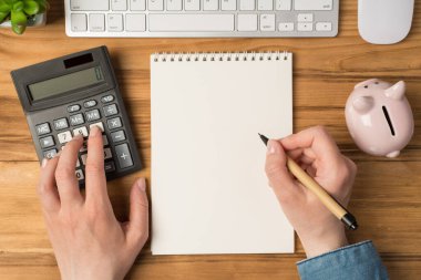 Kadın ellerinin hesap makinesine dokunduğu ve kalemi boş arkaplan ile izole edilmiş ahşap masa arkaplanındaki klavye fare kumbarasının üzerine koyduğu ilk kişi.