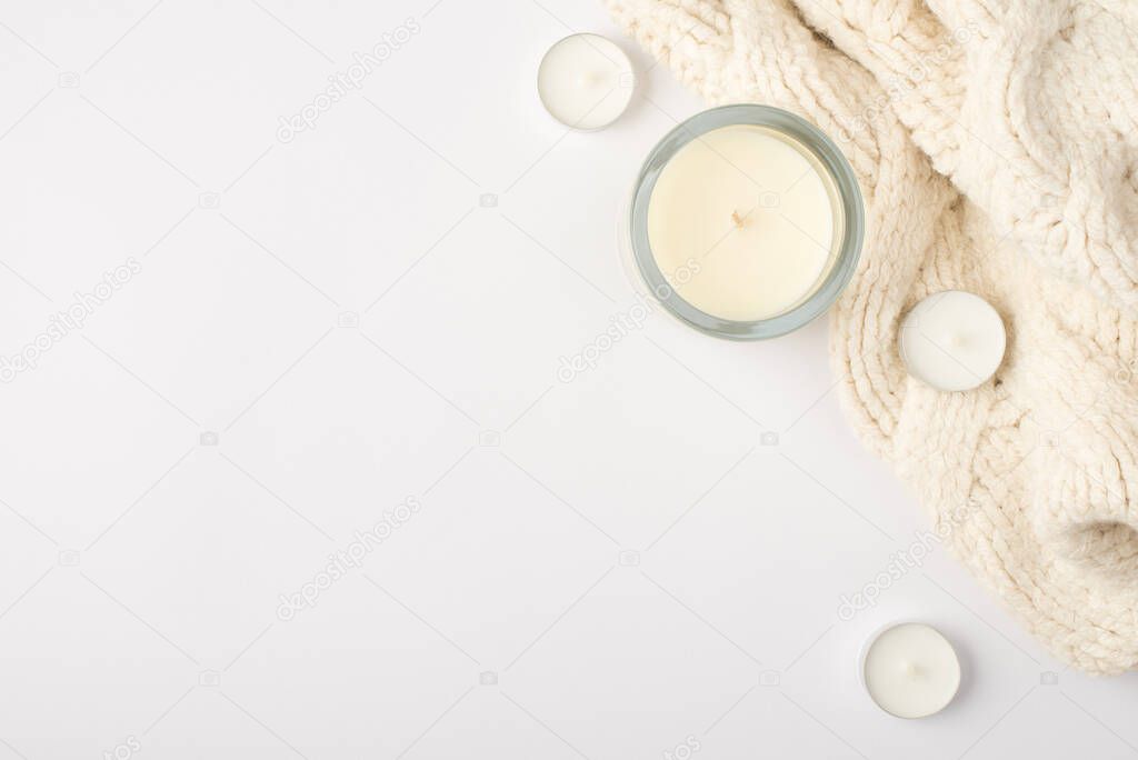 Top view photo of candles and white knitted scarf on isolated white background with copyspace