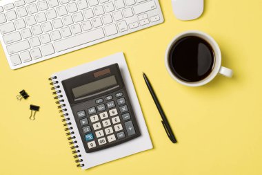 İşyeri beyaz klavye fare hesap makinesinin üst görünümü kahve fincanı ve izole edilmiş pastel arka planda kalem.
