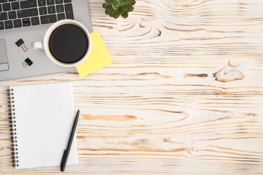 İçki klasörü fincanının en üst görüntüsü. Laptop bitkisi üzerine sarı etiket kağıdı ve kopyalanmış parlak ahşap masa arkaplanı üzerine kopya defteri üzerine kalem.