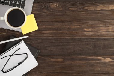 En üstteki fotoğrafta, dizüstü bilgisayardaki sarı etiket kağıdı beyaz kalem gözlüklü, iki siyah beyaz planlamacı izole edilmiş, ahşap masa arka planında, kopyalama alanı olan