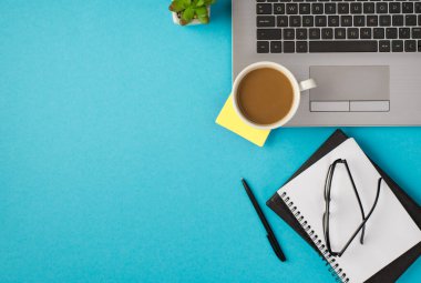 Dizüstü bilgisayardaki kahve fincanı etiketinin en üstteki fotoğrafı. Çiçek kalemi ve organizatörlerin gözlüğü.