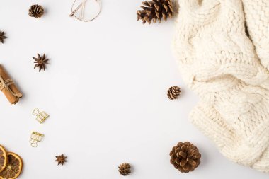 Beyaz örülmüş süveter kozalakları kurutulmuş limon dilimleri tarçın çubukları altın cilt klipsleri ve izole edilmiş beyaz arka planda gözlük ve ortada kopyalanmış boşluk.