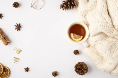 Limon kozalaklı beyaz örülü süveter fincanı kurutulmuş limon dilimleri tarçın çubukları izole edilmiş beyaz arka planda altın cilt tokaları ve bardaklar.