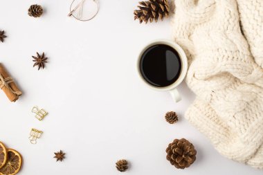 Beyaz örülmüş eşarp fincanının üst görüntüsü kahve kozalakları kurutulmuş limon dilimleri tarçın çubukları izole edilmiş beyaz arka planda altın cilt tokaları ve gözlükler.