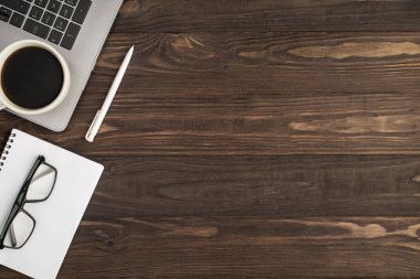 En üstteki fotoğrafta dizüstü bilgisayarda beyaz kalem ve beyaz düzenleyicide gözlük boş arkaplanda izole edilmiş siyah ahşap masa arkaplanı.