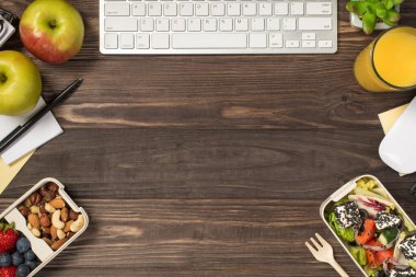 İş yerinin üst görüntüsü. Sağlıklı besin çatalı kırtasiyeli iki beslenme çantası. Köşelerde fare elması, meyve suyu bardağı.