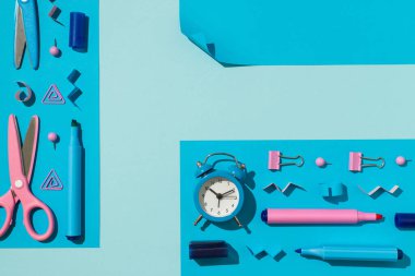 Mavi ve pembe okul malzemelerinin üst görünümü ve mavi dikdörtgen kağıt kağıtlar kağıt işaretler cilt raptiyeler makas ve izole edilmiş açık mavi zemin üzerindeki alarm saati