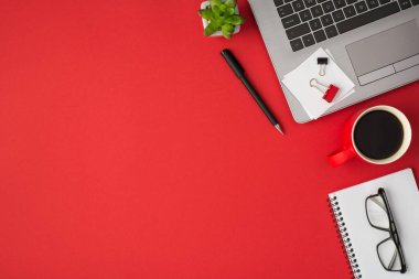 Klasör kliplerinin en üst görünümü beyaz etiket kağıdı dizüstü bilgisayar bitkisi kırmızı bardak içki ve kopyalanmış kırmızı arkaplan üzerinde gözlük