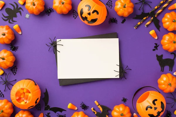ハロウィンの装飾のトップビューカボチャのバスケットキャンディーコーンウェブ猫のコウモリのシルエットは 空白のスペースで隔離された紫色の背景に白いカードの上に黒い封筒とクモを撫でています — ストック写真