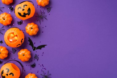 Cadılar Bayramı süslemelerinin en üstteki fotoğrafı balkabağı sepetleri mısır şekeri siyah pullar örümcekler ağ ve kopyalanmış menekşe arkaplan üzerinde yarasa silueti