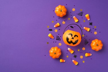 Cadılar bayramı süslemelerinin en üst görüntüsü balkabağı sepeti şeker mısır pul altın yıldızlar yarasa örümcek ağı siluetleri izole edilmiş menekşe arkaplan