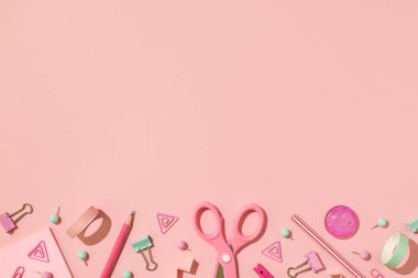 Makas fotografının üstünde bant ataçları kalem iğneleri ve pembe zemin üzerinde boş alan ile izole edilmiş spiraller.