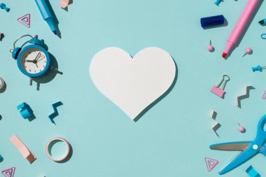 Beyaz kağıt kalp bicolor mavi ve pembe kırtasiye işaretleri bağlayıcı raptiyeler yapışkan bant makası ve izole edilmiş pastel mavi zemin üzerindeki alarm saati